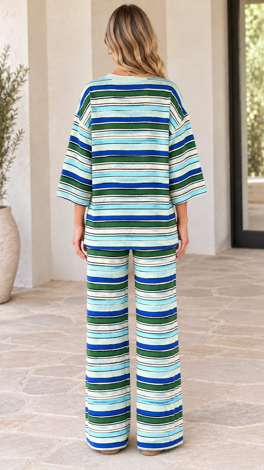 Back view of model wearing oversized striped knit top and coordinating trousers
