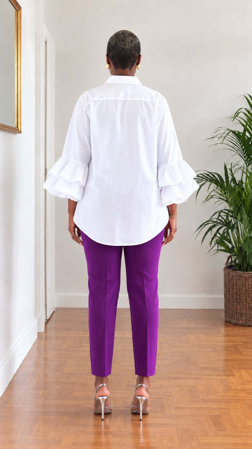 Back view of woman wearing white long sleeve tiered ruffle blouse showing tunic back length