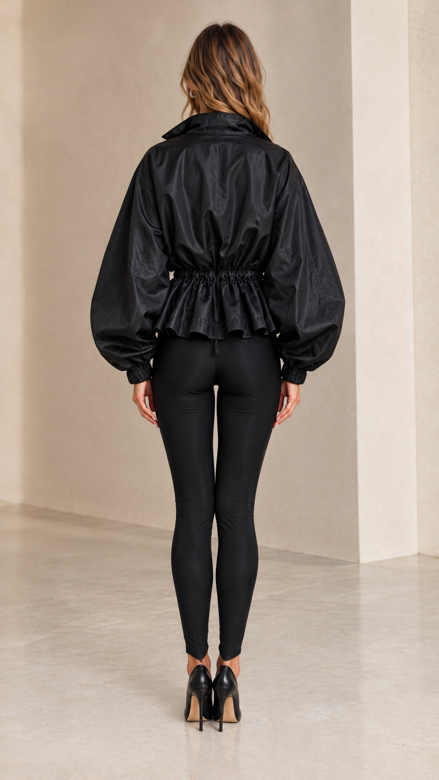 Back view of model wearing black cinch-waist peplum jacket with balloon sleeves