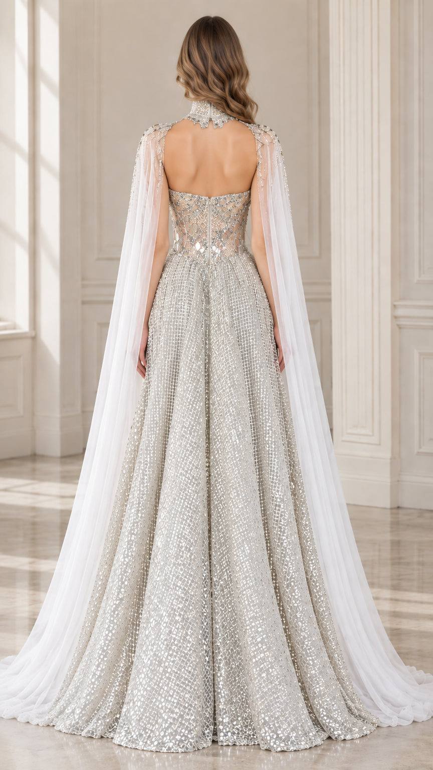 Back view of model showing open back design and sweeping white cape of the silver gown