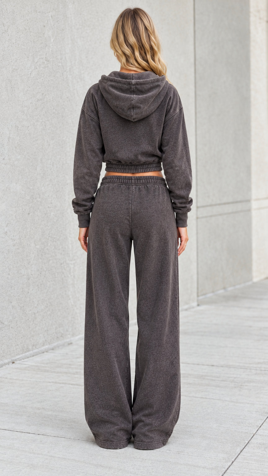 Back view of model wearing washed charcoal cropped hoodie with hood up and relaxed sweatpants