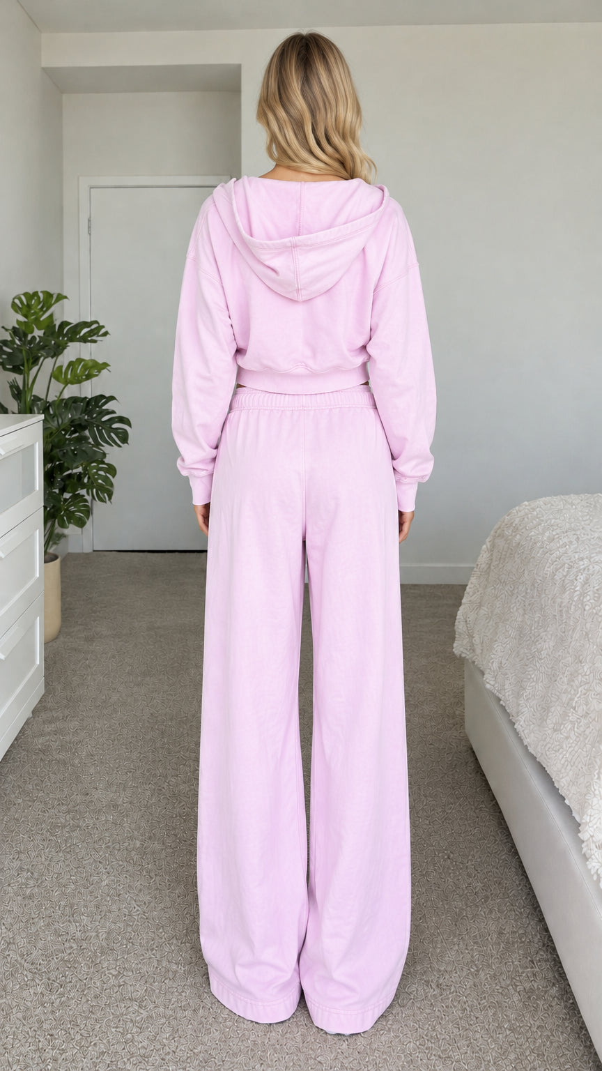 Back view of model wearing light pink hooded sweatshirt and wide-leg pants