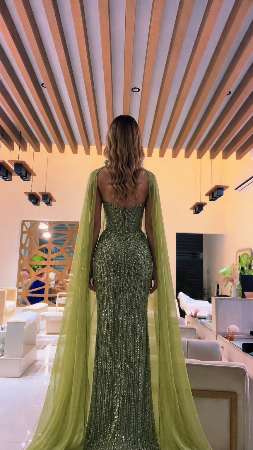 Back view of olive green sequined column dress showing flowing cape drape