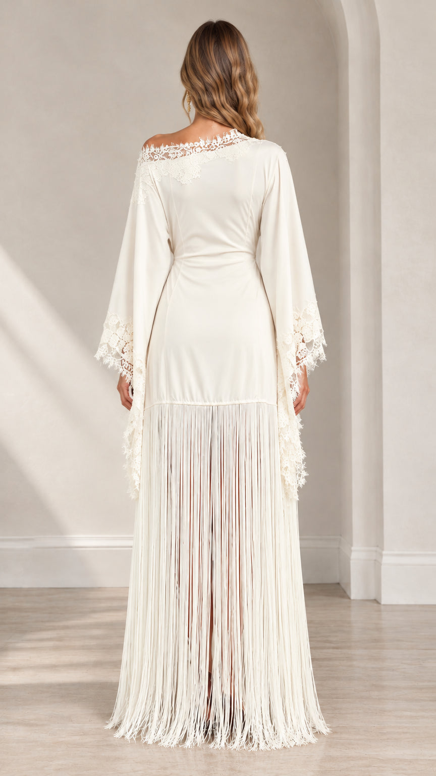 Back view of woman wearing ivory maxi dress with draped sleeves and fringe hem