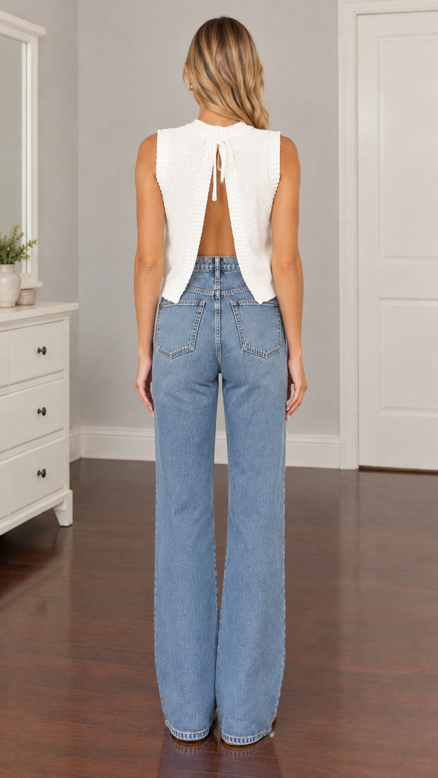 Back view of model showing open back cutout with tie closure on white knit top