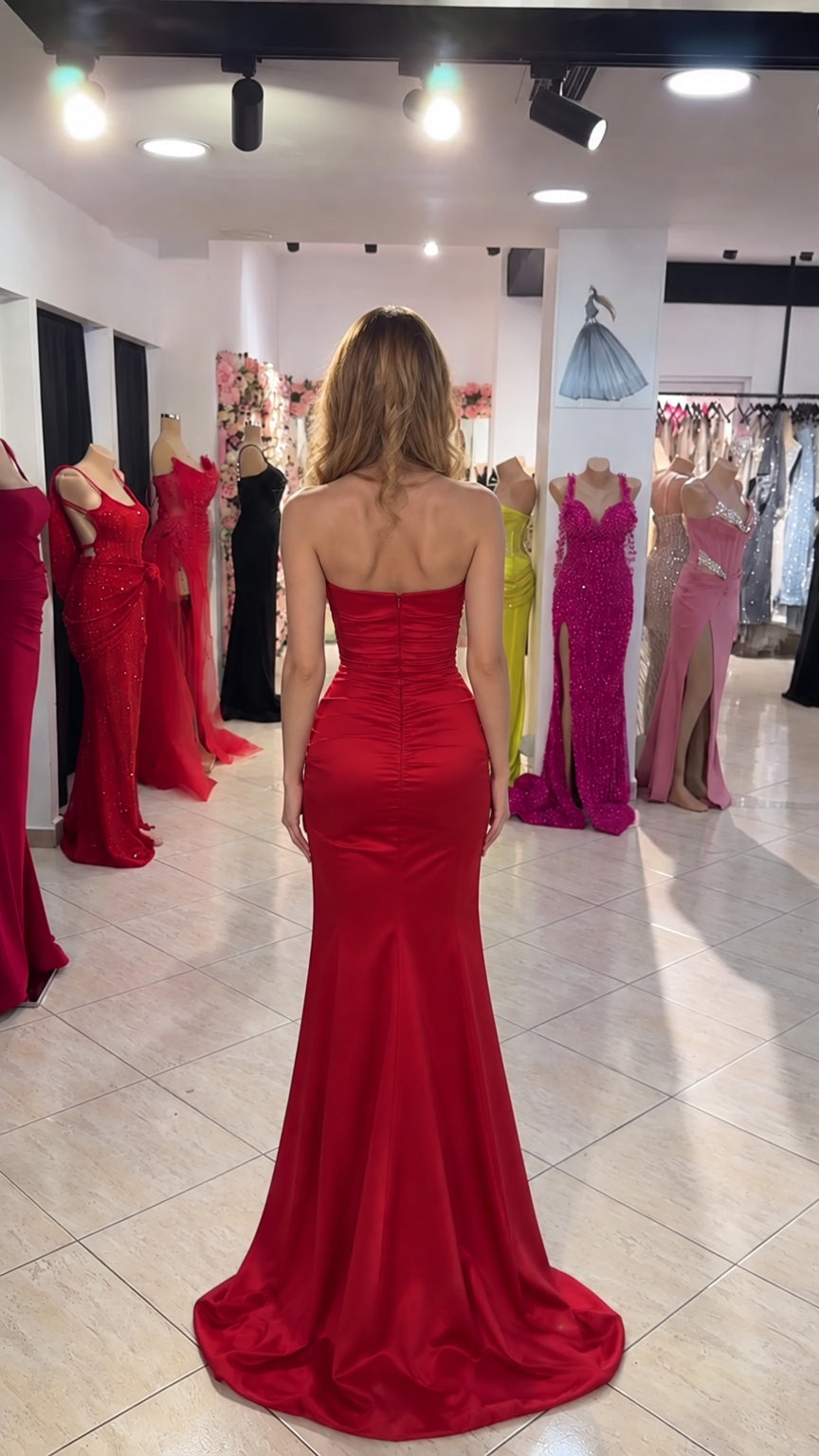 Back view of model showcasing strapless back and flowing red satin train