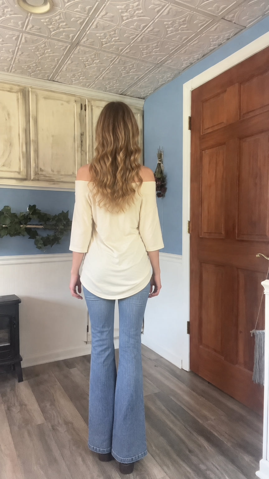 Back view of model wearing beige off the shoulder graphic tunic top