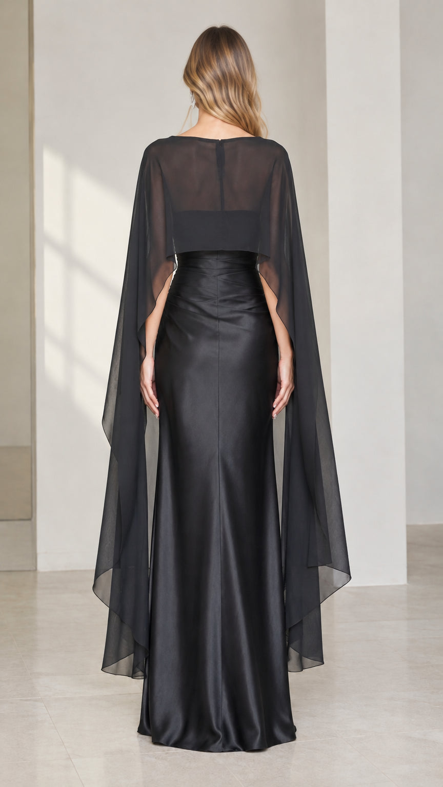 Back view of black satin column dress with flowing sheer overlay cape