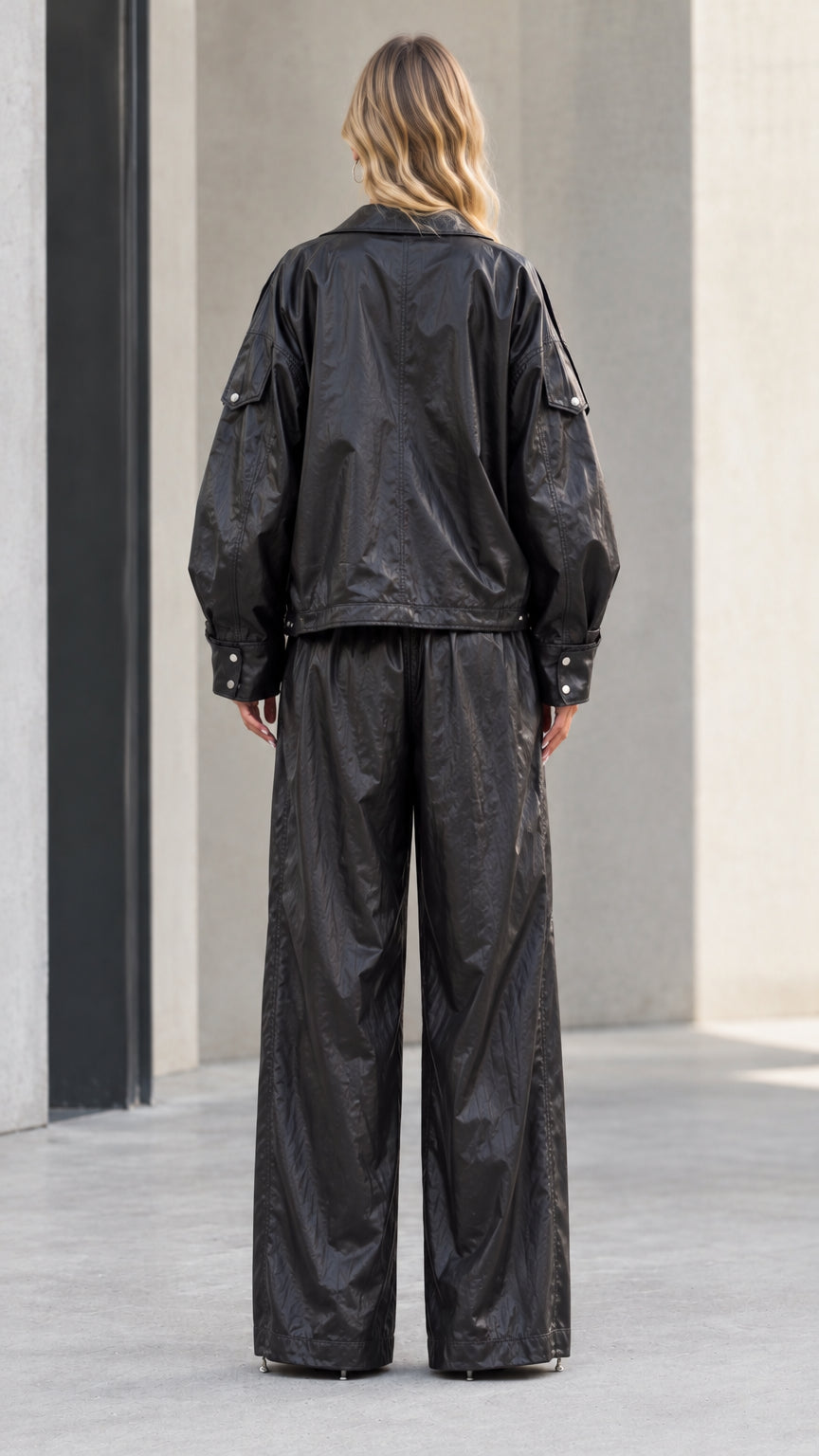 Back view of model showcasing relaxed fit of black metallic jacket and wide leg pants