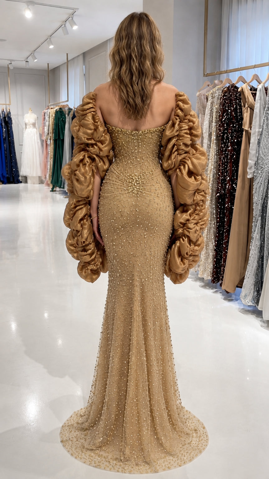 Back view of gold floor-length embellished mermaid gown showing back neckline and sleeve volume