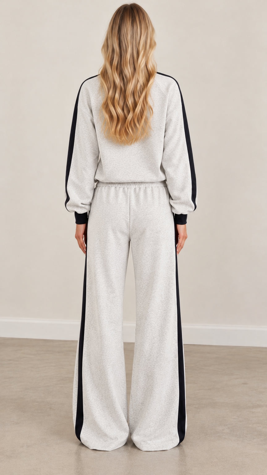 Back view of model wearing heather gray loungewear set with black sleeve and leg stripes