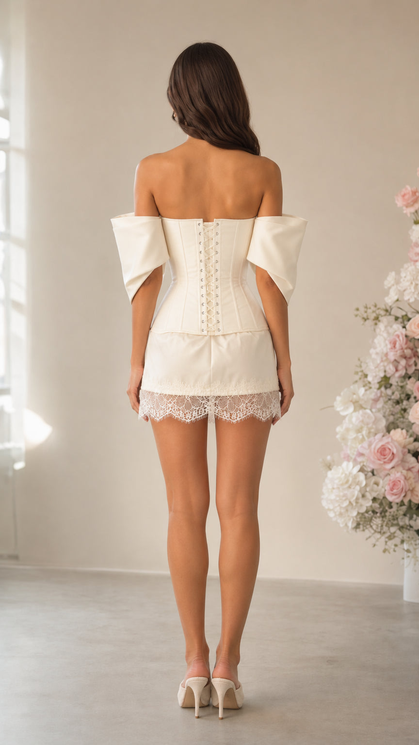 Rear view of model showing lace-up back closure of ivory corset mini dress