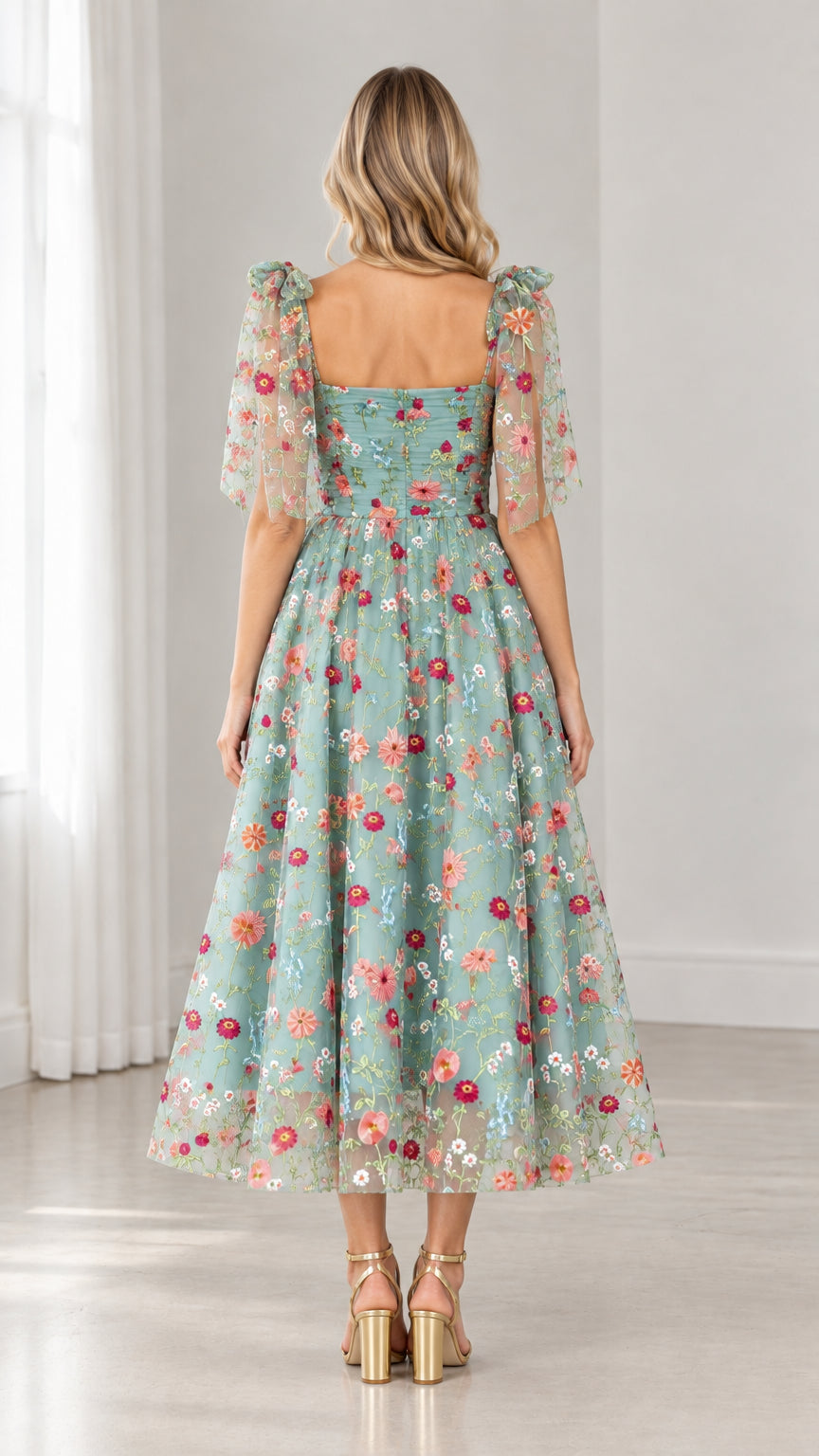 Back view of model showing open back and flared skirt of sage green embroidered midi dress