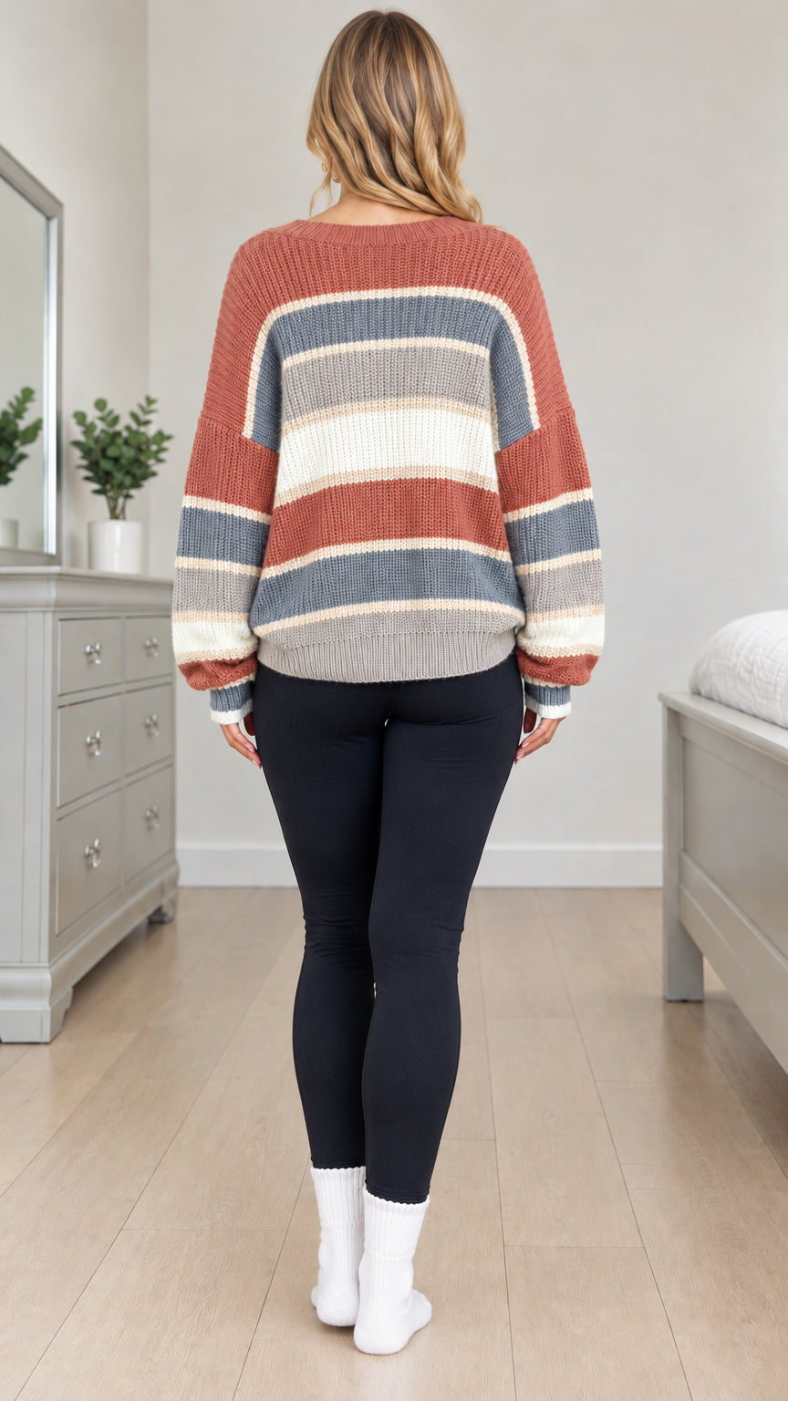 Back view of model wearing rust striped crewneck knit sweater with drop shoulder design