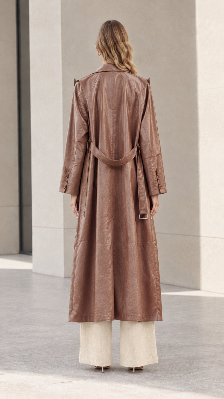 Back view of model showing the belted detail and full length of the brown trench coat
