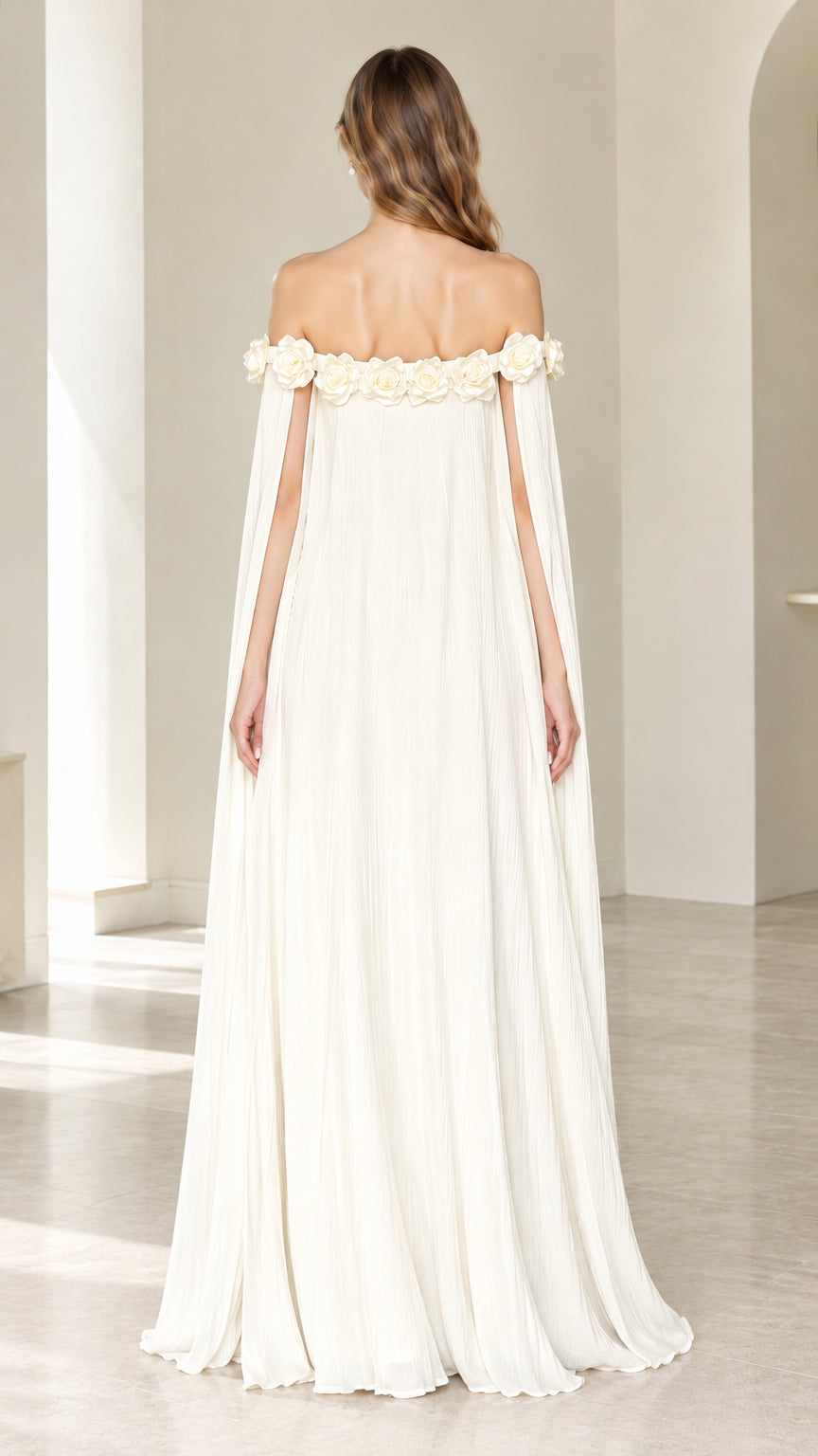 Back view of model wearing Ivory off-the-shoulder rosette trim cape dress