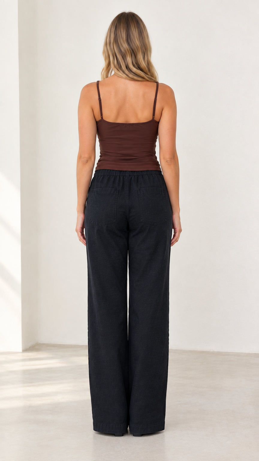 Back view of woman wearing brown strap cami and black full length trousers