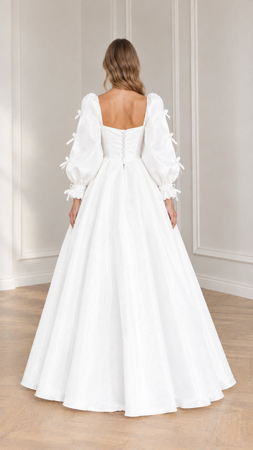 Back view of model in white ballgown showing lace-up corset detail and full skirt