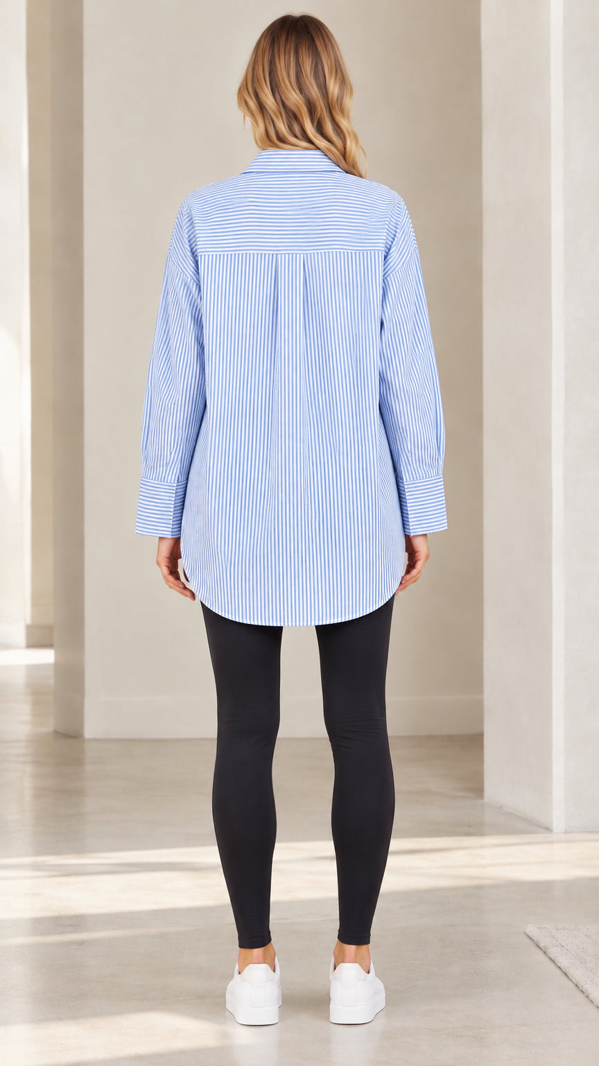 Back view of model wearing light blue striped long sleeve tunic shirt with back yoke detailing