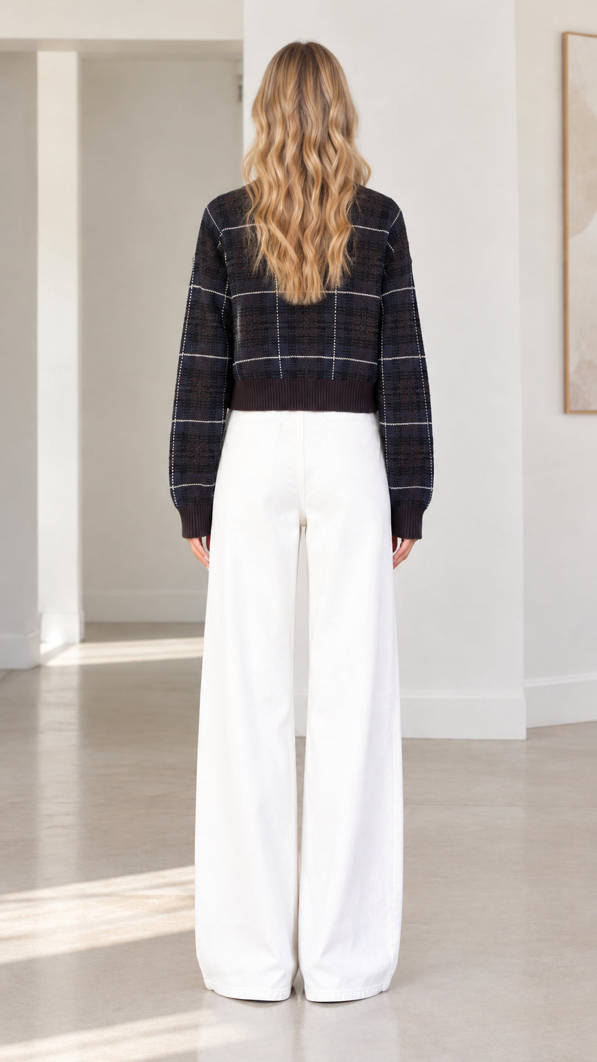 Back view of woman wearing black plaid cropped cardigan sweater and white wide-leg trousers