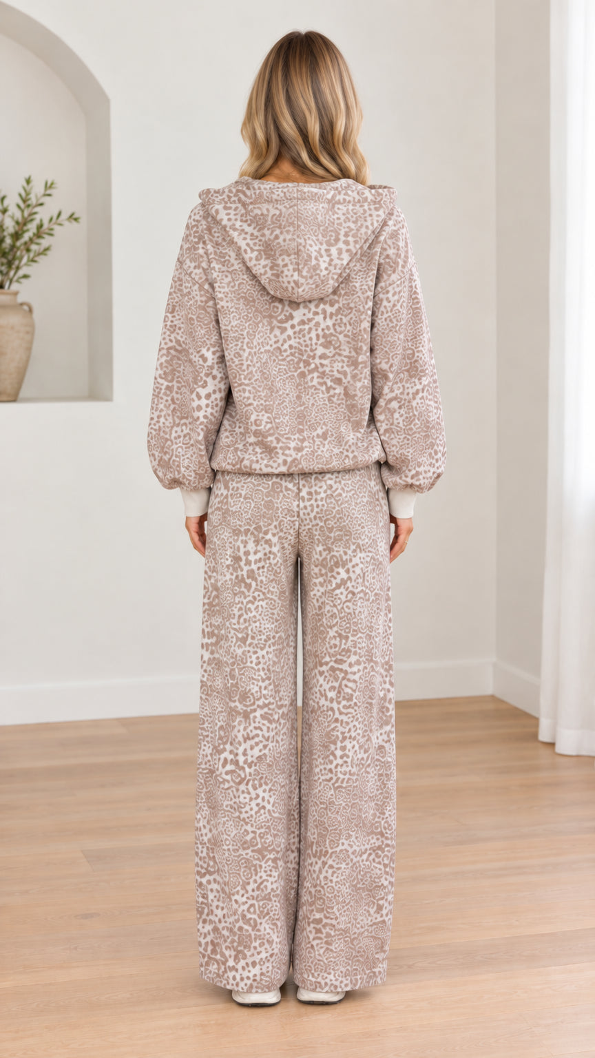 Back view of woman wearing taupe leopard print hooded jacket and wide-leg trousers