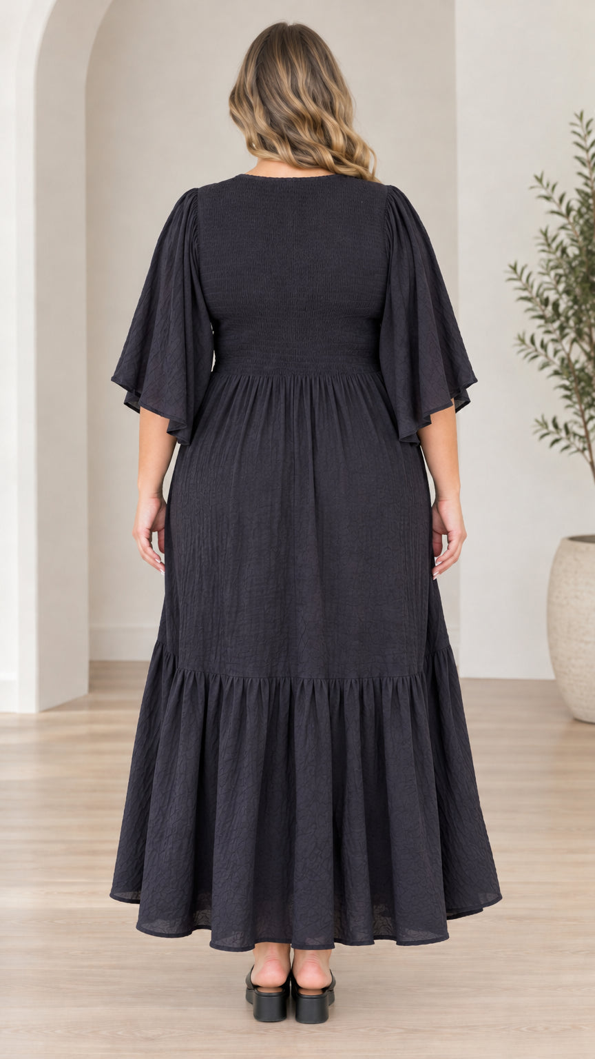 Back view of model wearing black smocked tiered maxi dress
