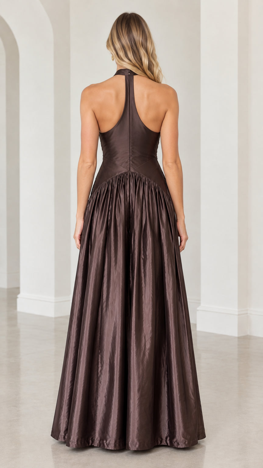 Back view of model in chocolate brown halter satin maxi gown highlighting racerback silhouette