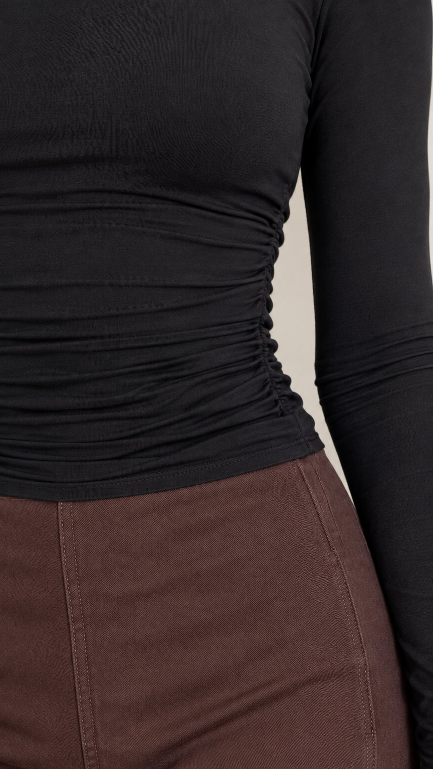 Close-up detail of side ruching on long sleeve top and waistband seam