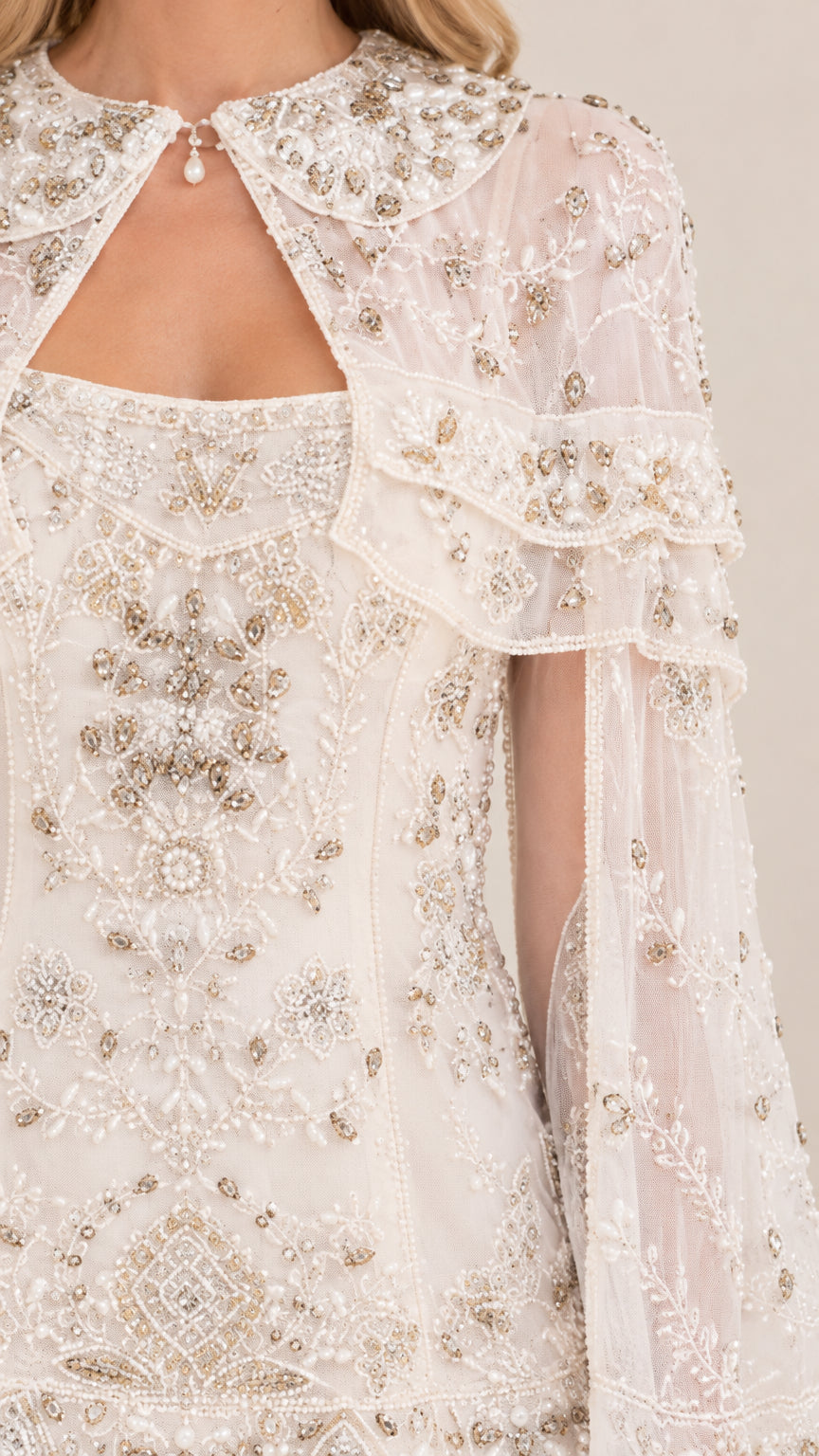 Close-up detail of intricate bead and sequin embroidery on ivory dress neckline and capelet