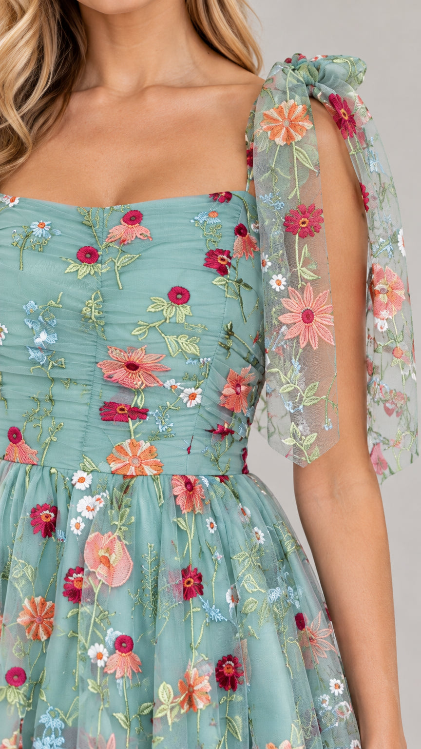 Close-up detail of multi-colored floral embroidery and ruched square neckline on sage green dress
