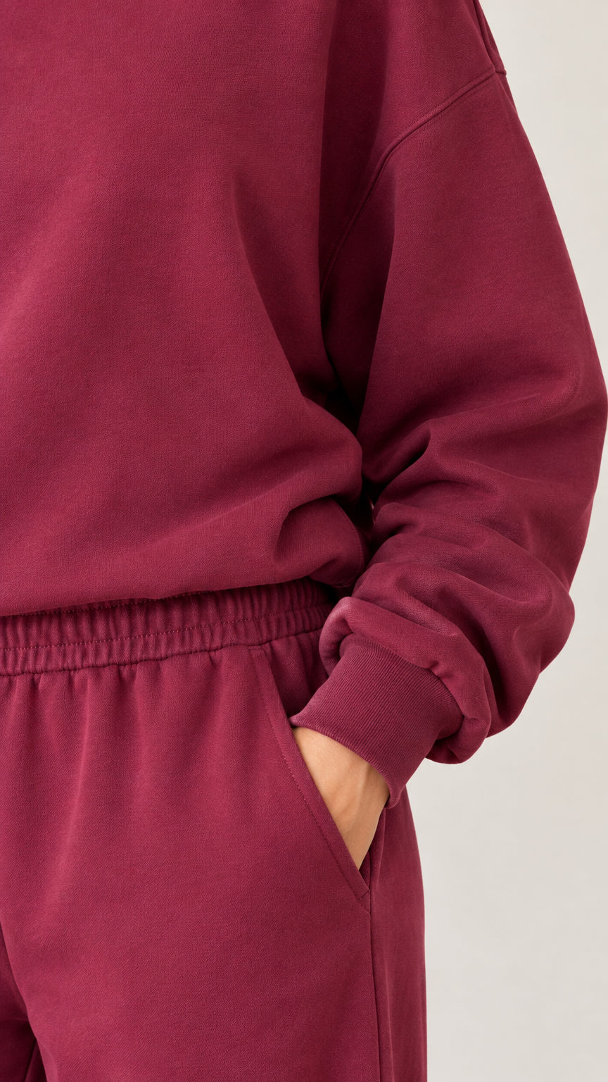 Close-up detail of burgundy sweatshirt ribbed cuff and elastic waistband with pocket