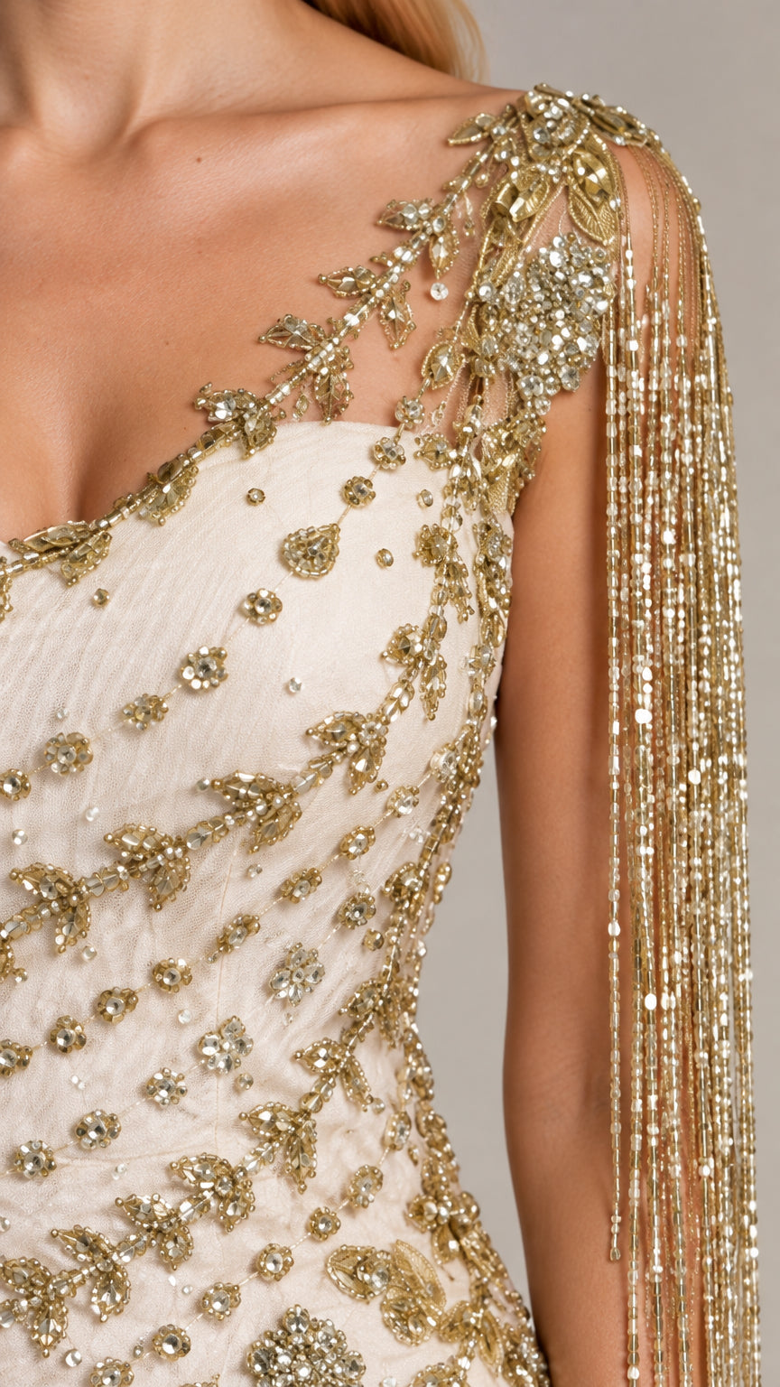 Close-up detail of delicate gold floral beadwork and cascading shoulder fringe