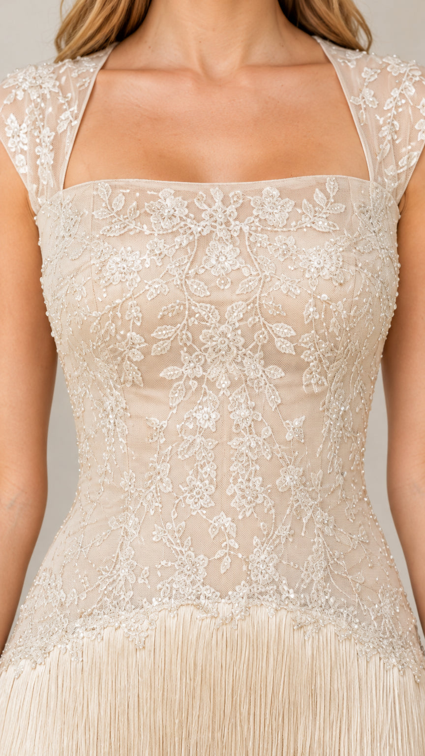 Close-up detail of champagne floral embroidered lace bodice and fringe connection