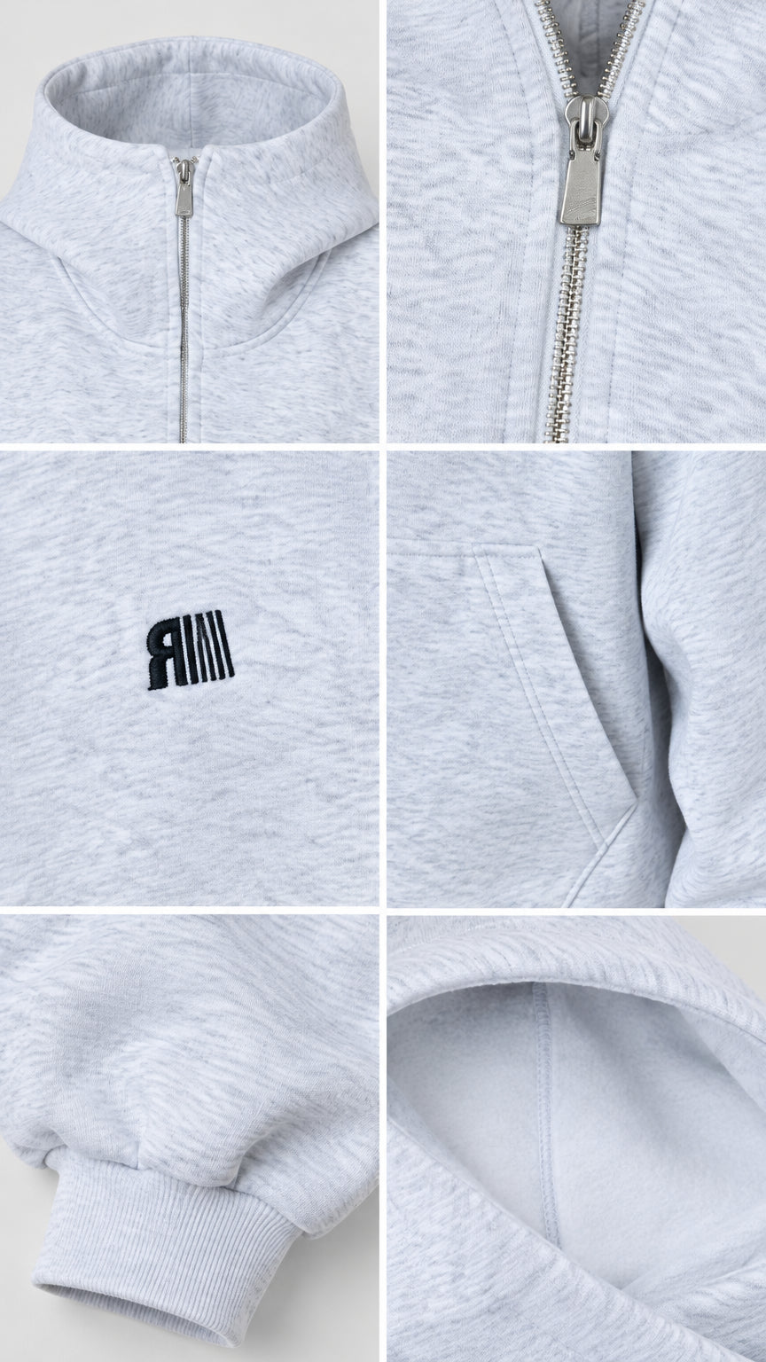 Close-up details of heather grey hoodie showing high zip collar, metal zipper pull, embroidered chest logo, side pocket, ribbed cuff, and fleece lining
