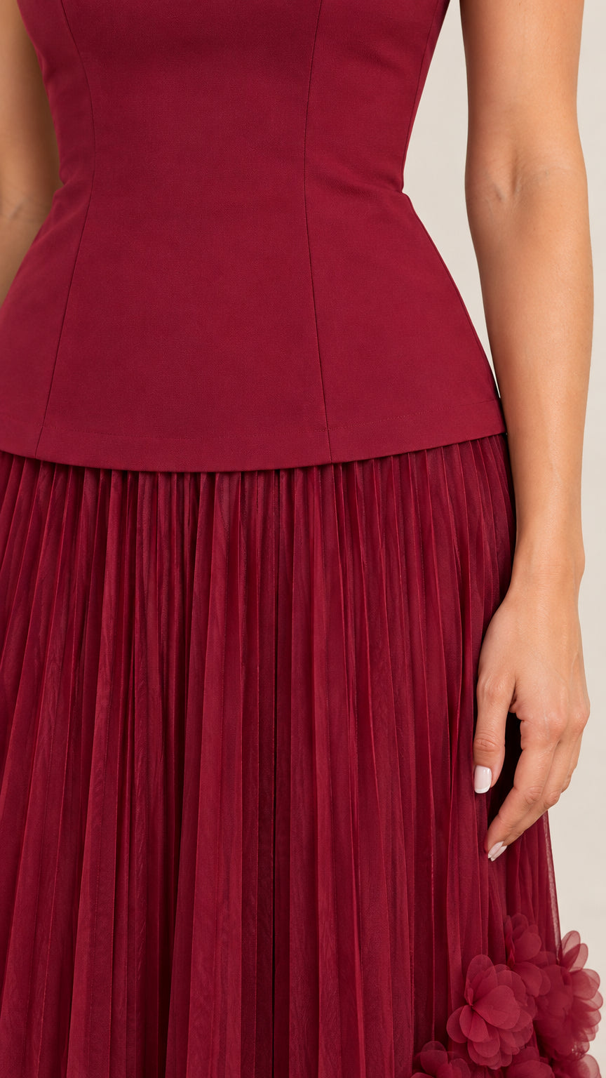 Close-up detail of structured waistline and pleated skirt fabric in burgundy