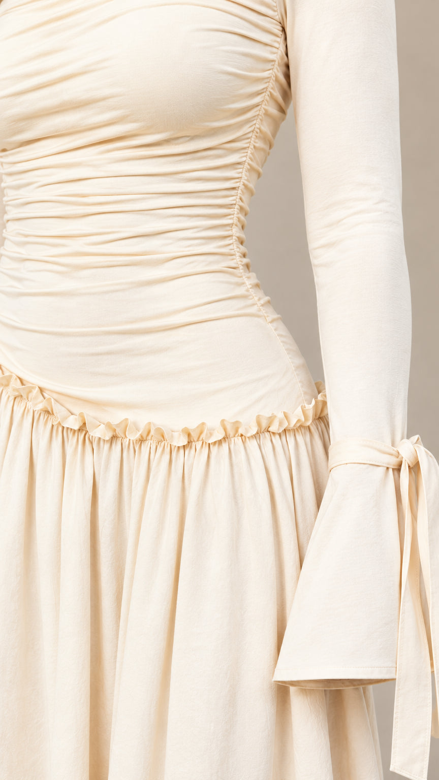 Close-up detail of bodice ruching, asymmetric frill waistline, and flared sleeve with tie