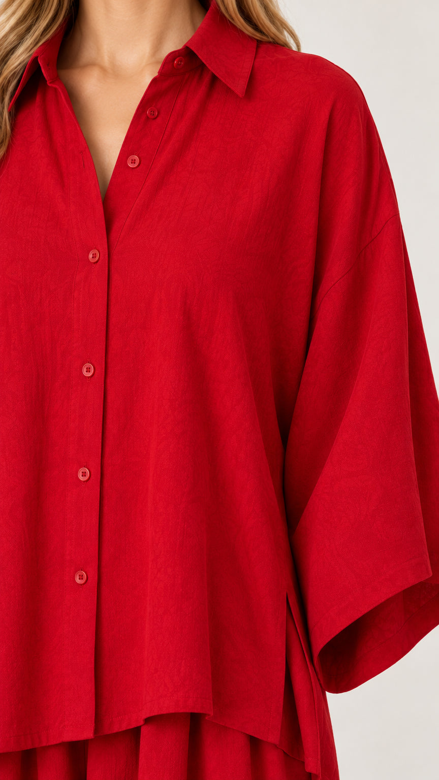 Close-up detail of red button-down shirt neckline, collar, and relaxed sleeve construction