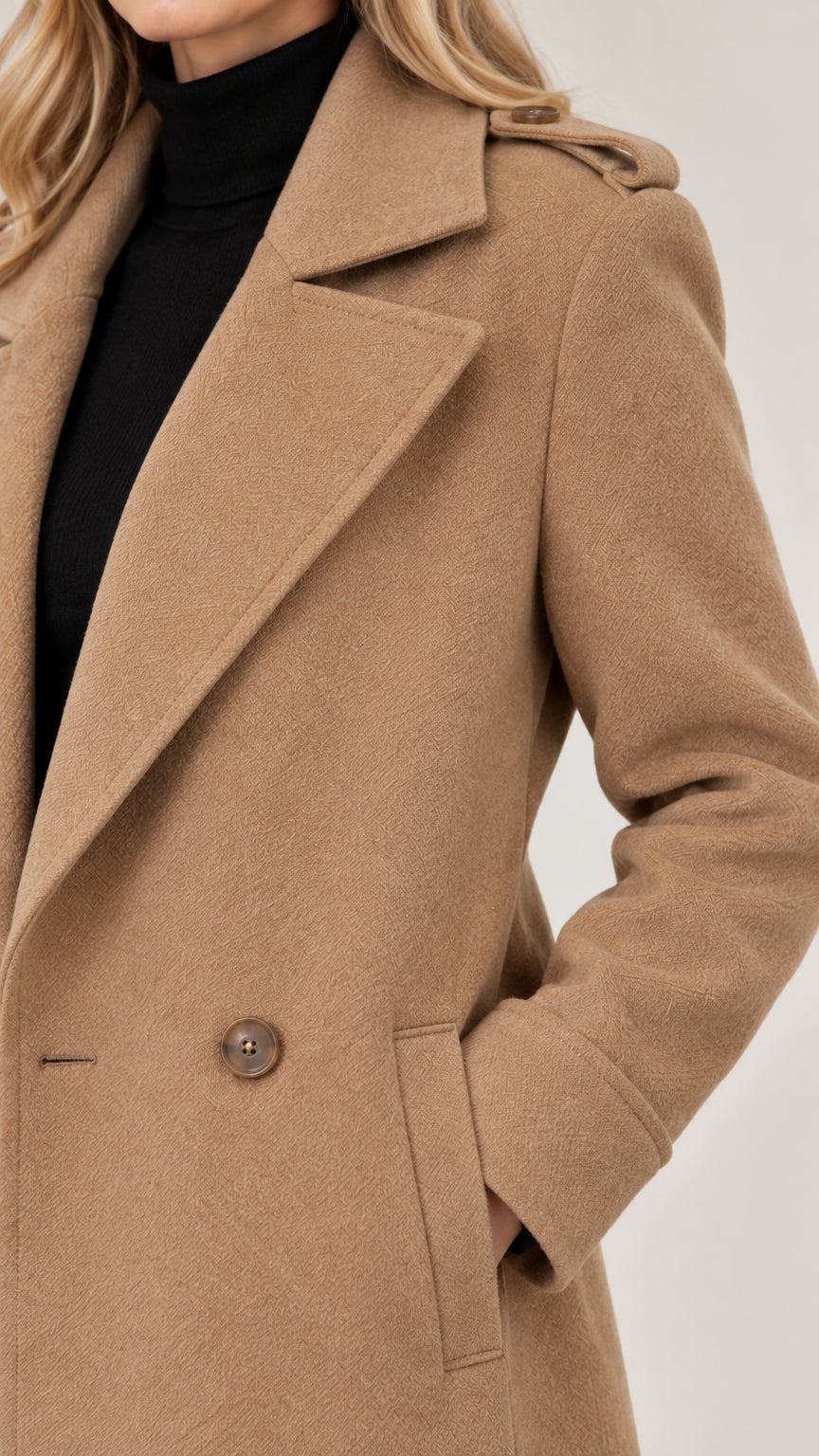 Close-up detail of the notch lapel, shoulder epaulette, and side welt pocket on a camel coat