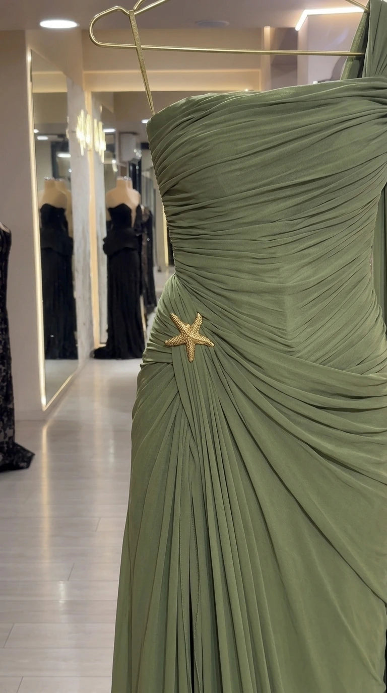 Close-up of the gathered pleats and gold starfish brooch pin on the olive gown