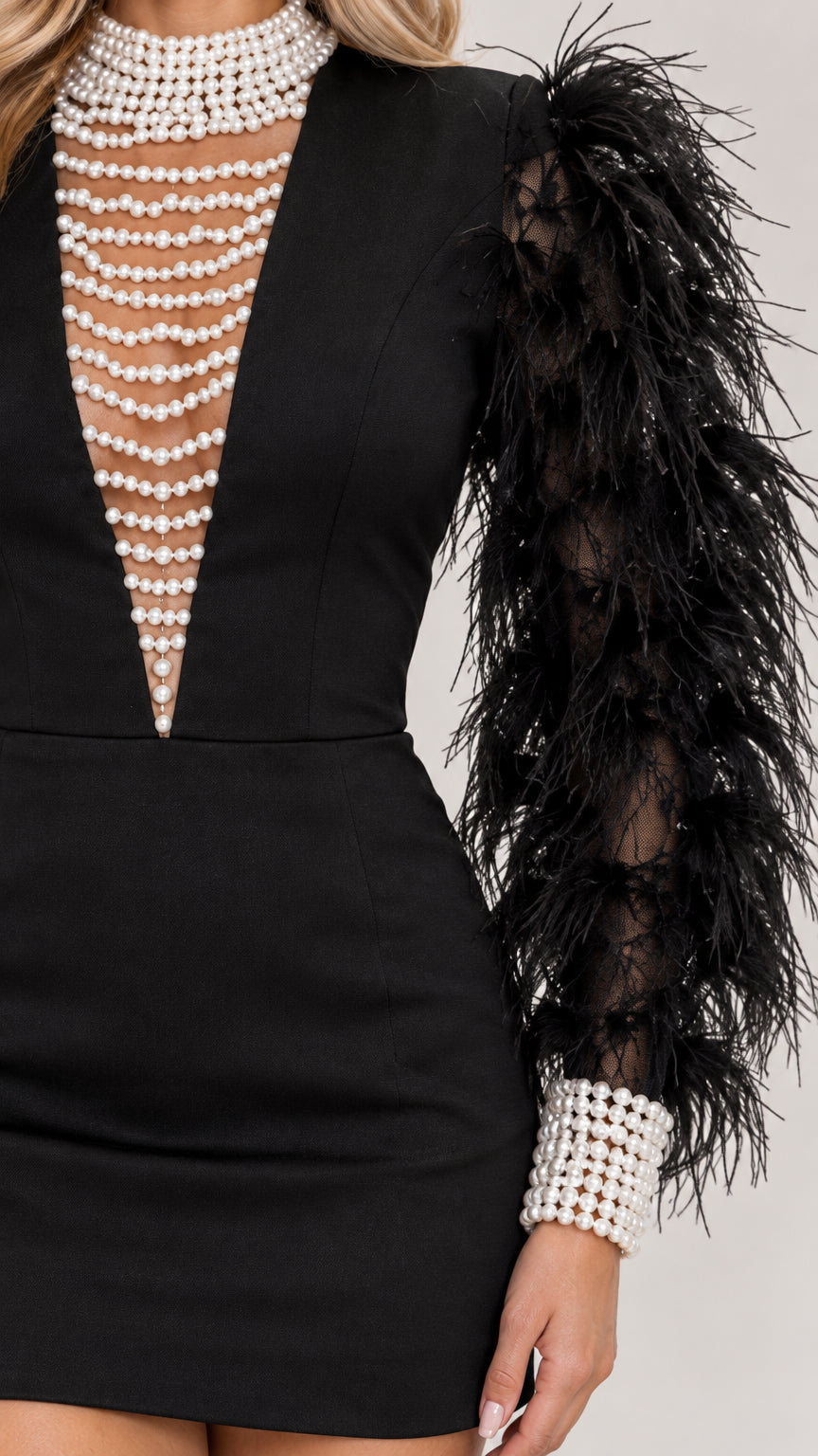 Close-up detail of faux pearl illusion neckline and textured feather sleeve with pearl cuff on black dress
