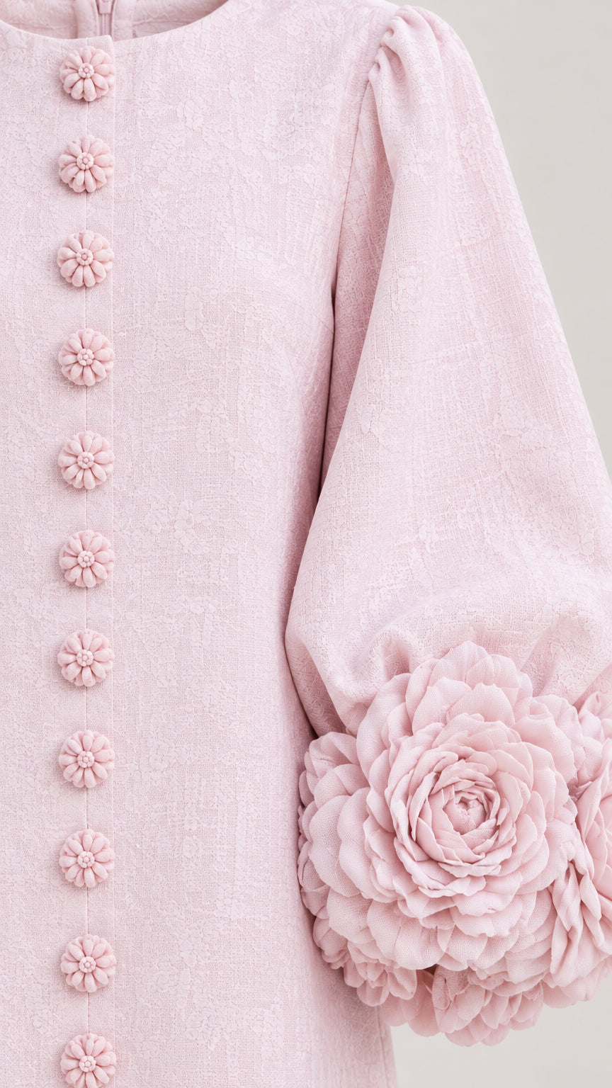 Close-up detail of blush pink textured fabric, floral buttons, and 3D flower cuff