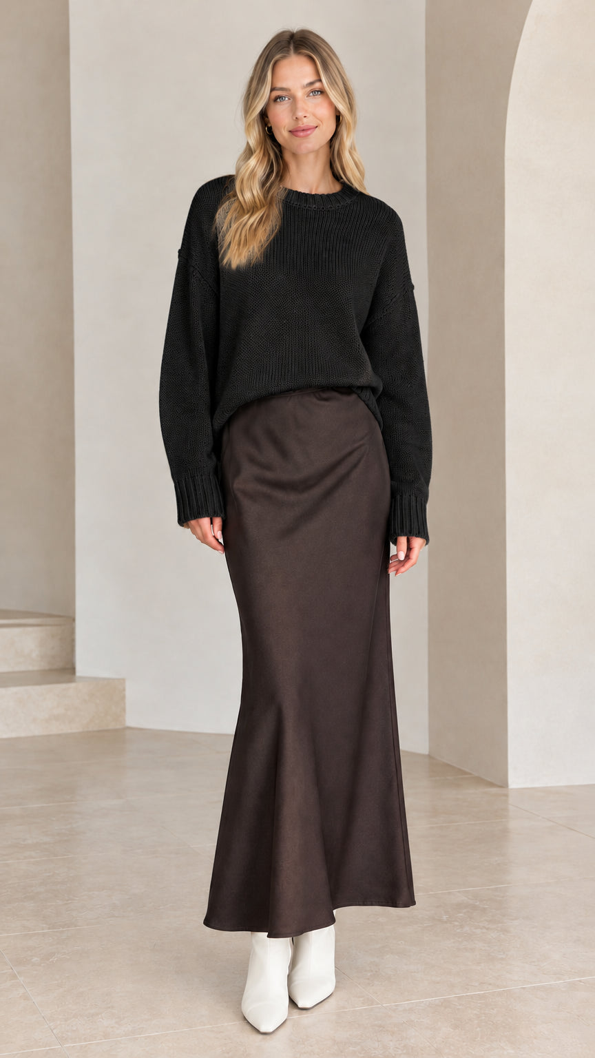 Model wearing black relaxed drop shoulder crew neck knit sweater with brown satin skirt