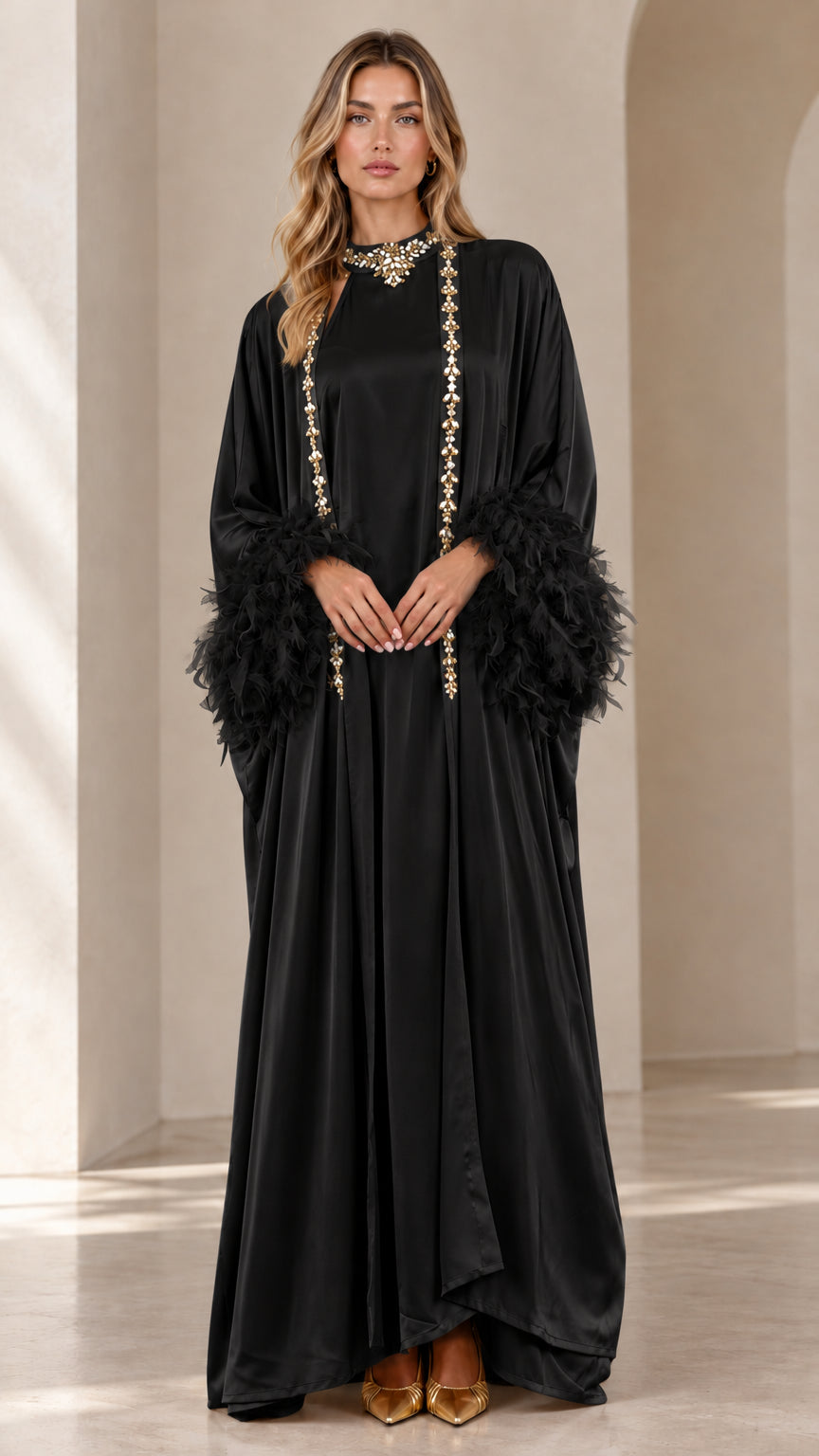 Front view of woman wearing black satin embellished maxi kaftan with feather cuffs