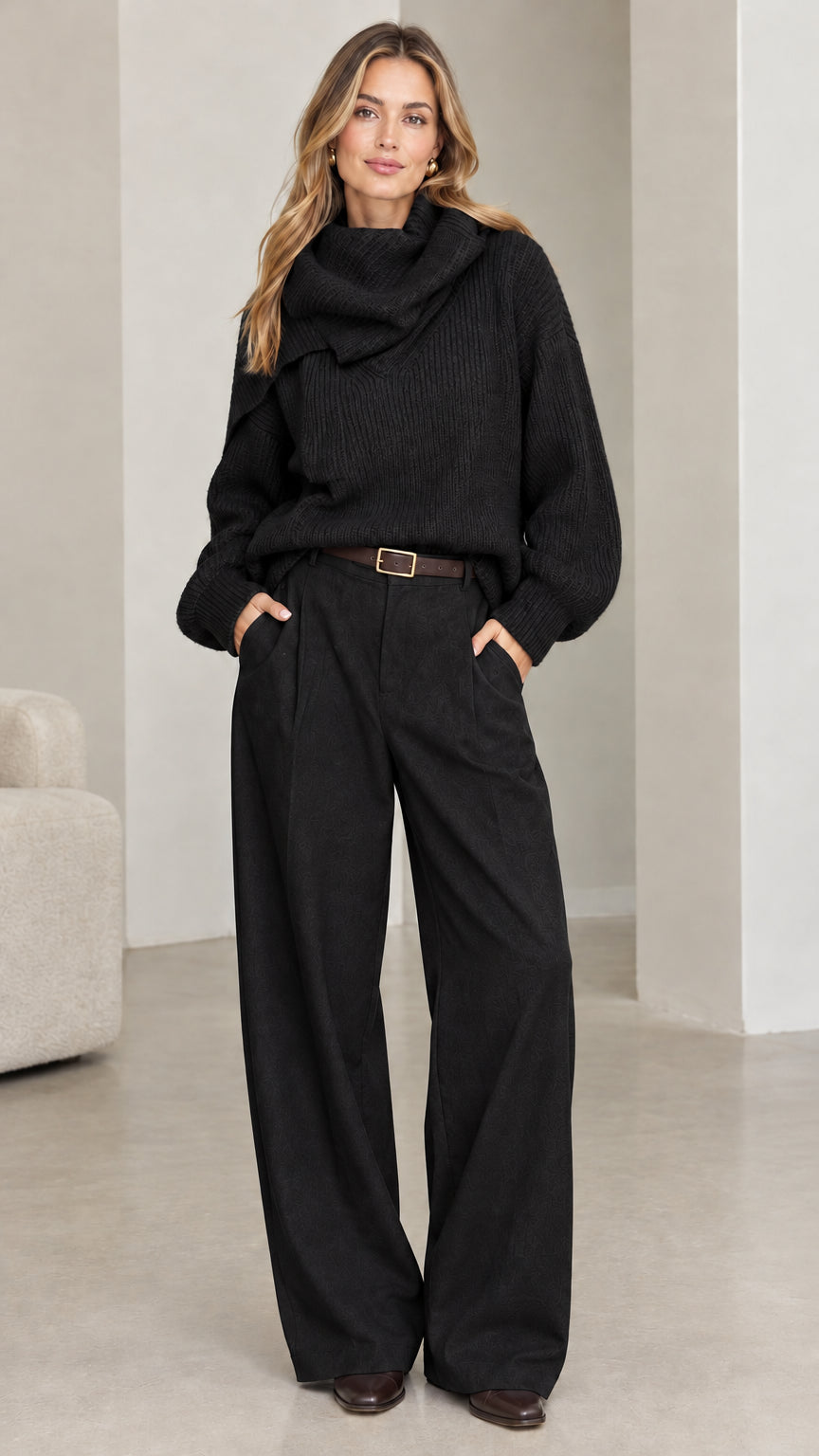 Front view of model wearing black ribbed knit cowl neck sweater with black trousers