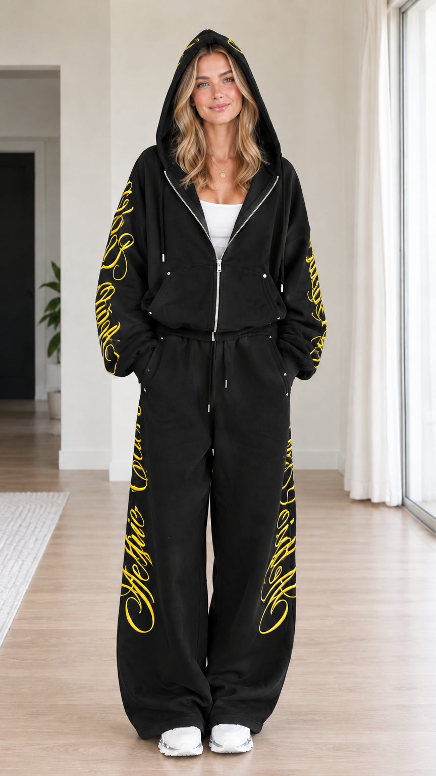 Front view of woman wearing black script embroidered zip-up hoodie and wide-leg sweatpants set