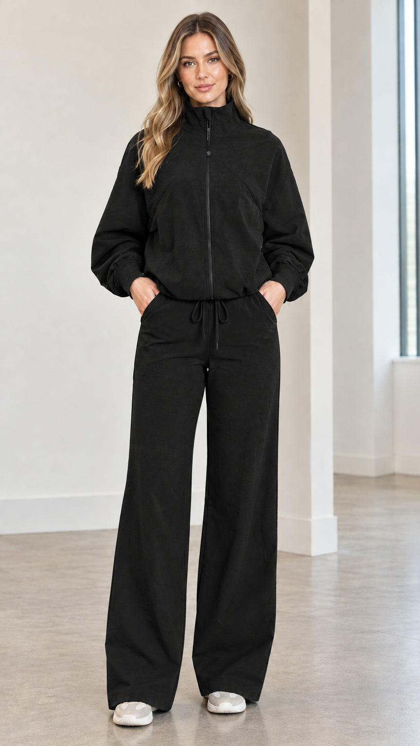 Front full view of woman wearing black zip-up track jacket and matching wide-leg pants