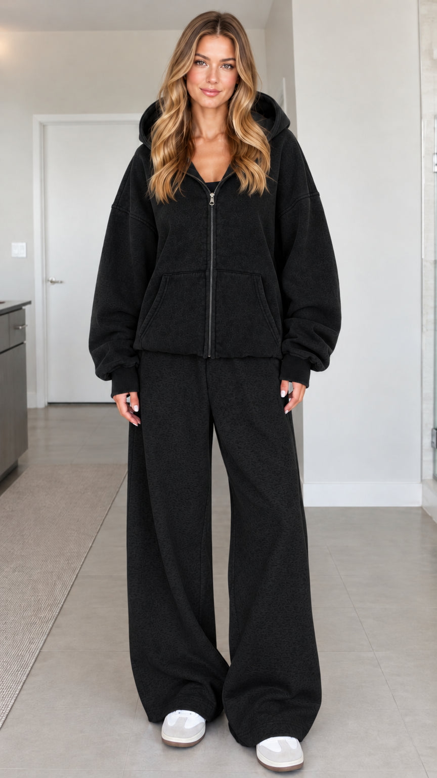 Front view of a woman wearing an oversized black zip-up hoodie with matching black wide-leg sweatpants