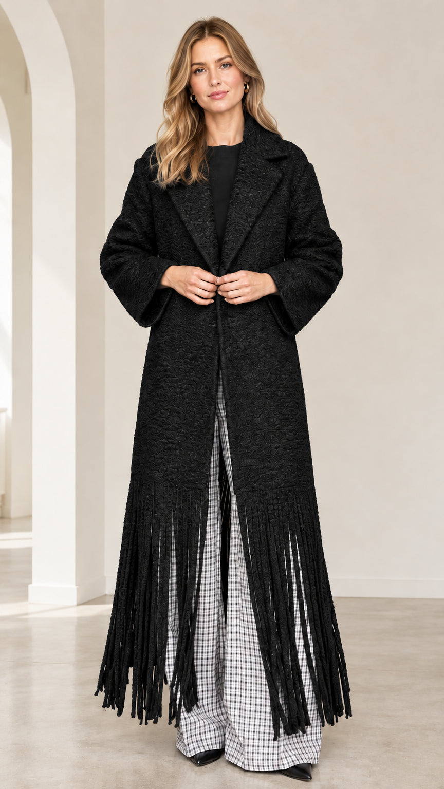 Front view of black textured bouclé maxi coat with fringe trim