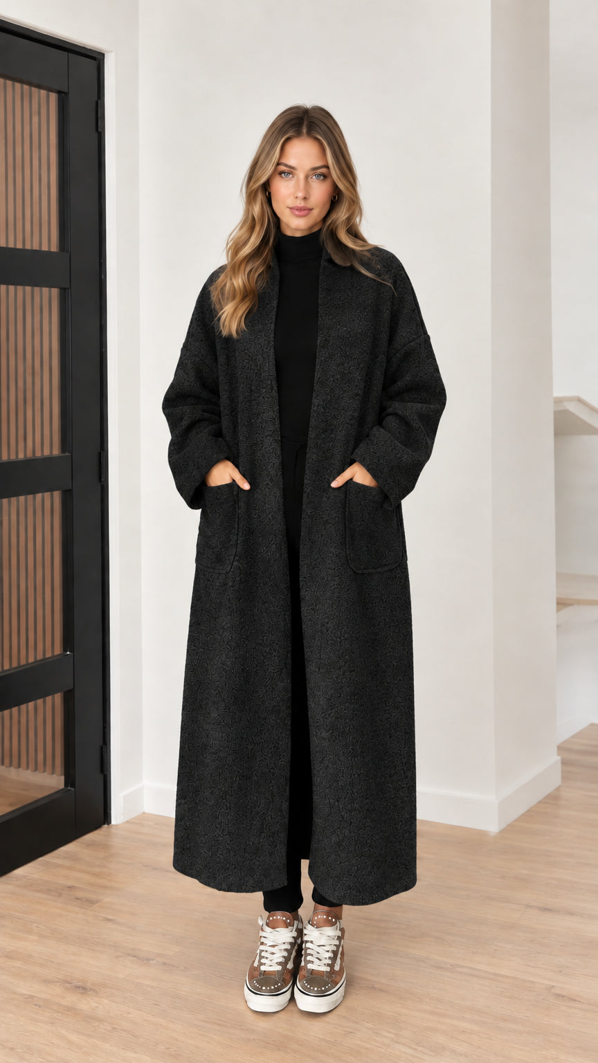 Front view of model wearing black textured maxi coat