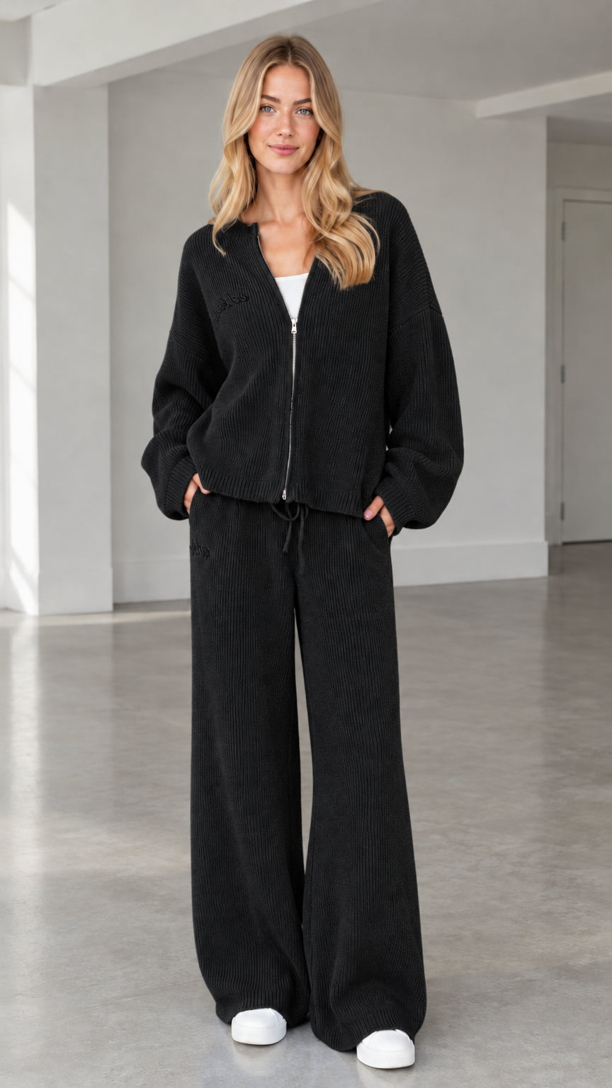 Front full view of woman wearing black ribbed knit zip-up cardigan and wide-leg pants set